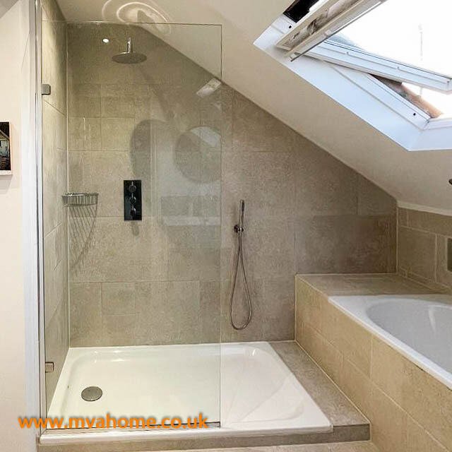 Fulham ensuite bathroom with frameless glass shower enclosure, grey stone tiles, wall-mounted shower panel, handheld shower, and a skylight above the bathing area.