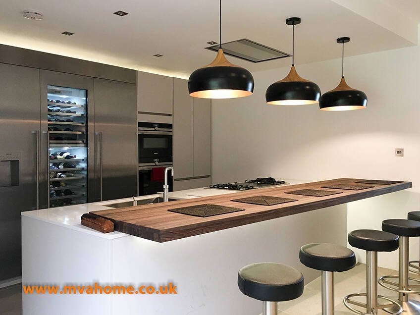 Modern London home kitchen with white cabinetry, warm pendant lighting and dark accents—one of the 5 interior design tips for better flow at home today.